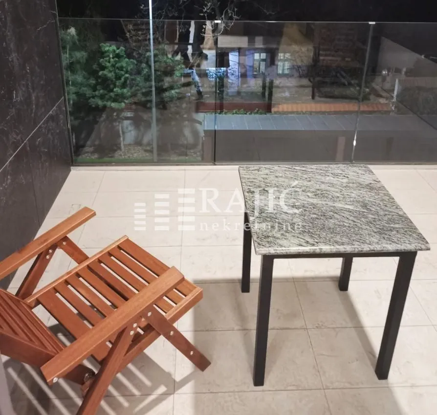 Covered terrace with a table and a wooden armchair.