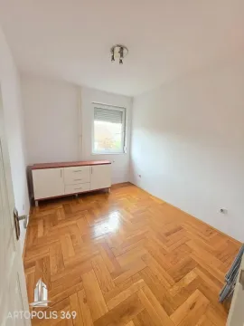 Prazna soba sa parketom i komodom ispod prozora. - image 6
