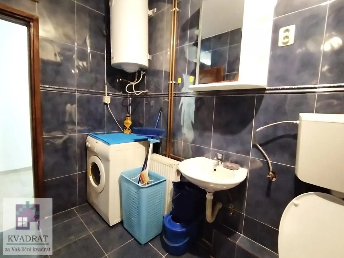 Small tiled bathroom equipped with a toilet, washbasin, and washing machine.