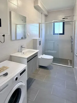 Savremeno opremljeno kupatilo sa tuš kabinom, umivaonikom i veš mašinom. - image 7