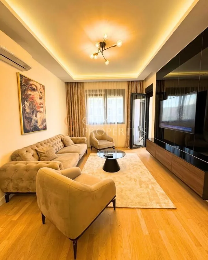 Modern living room furnished with a sofa, armchairs and a TV.