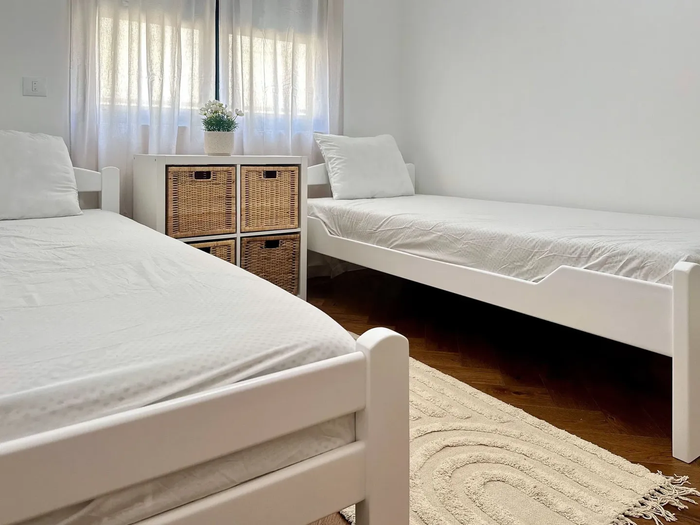 Bedroom with two single beds and a chest of drawers between the windows.