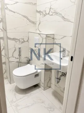 Small bathroom featuring white marble-effect ceramic tiles, a wall-hung toilet, and a sink. - image 3