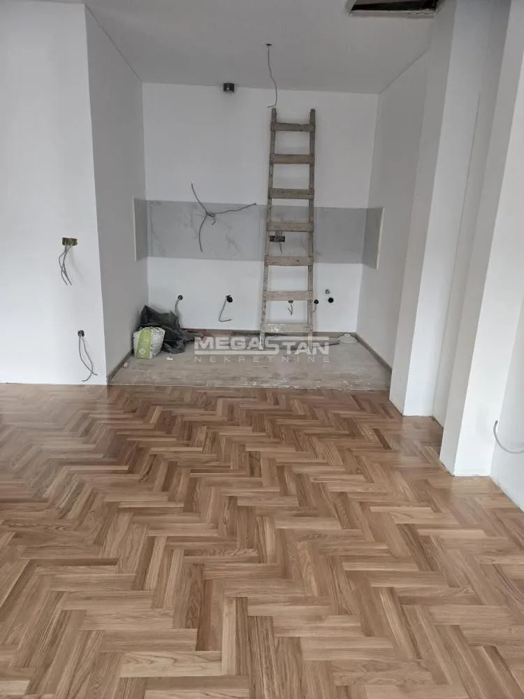 Prazna prostorija u toku renoviranja sa postavljenim parketom i merdevinama.