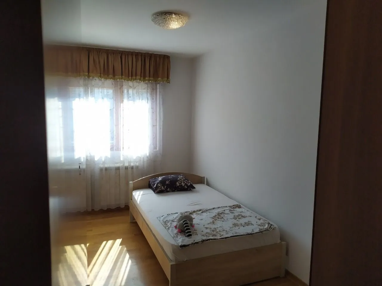 A simple bedroom with a single bed and a window.