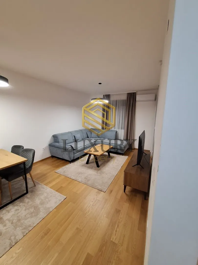 Living room with a sofa, dining table, and TV unit.