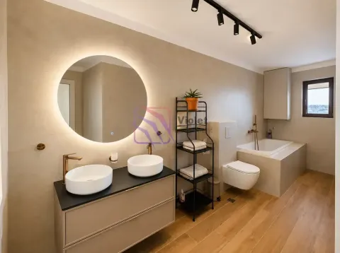 Modern bathroom with double sinks, round backlit mirror, and a bathtub. - image 18