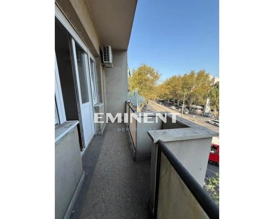 Long balcony with a view of the street and trees.