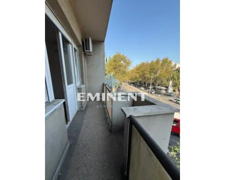 Long balcony with a view of the street and trees. - image 12