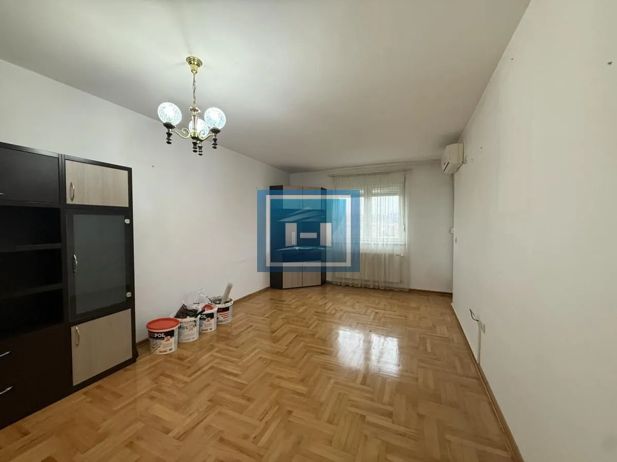 Empty living room with parquet flooring and a wardrobe.