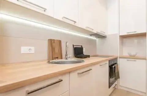 Modern kitchen with white cabinets and a wooden countertop. - image 8