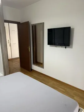 Dio spavaće sobe sa televizorom na zidu i otvorenim vratima. - image 4