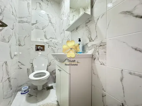 Small bathroom tiled with marble-pattern tiles, featuring a toilet and a sink. - image 7