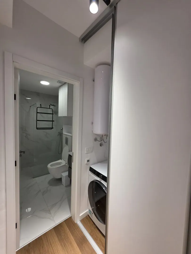 View from the hallway into a modern equipped bathroom and built-in washing machine.