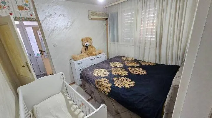 Namještena spavaća soba sa bračnim krevetom i krevetcem.