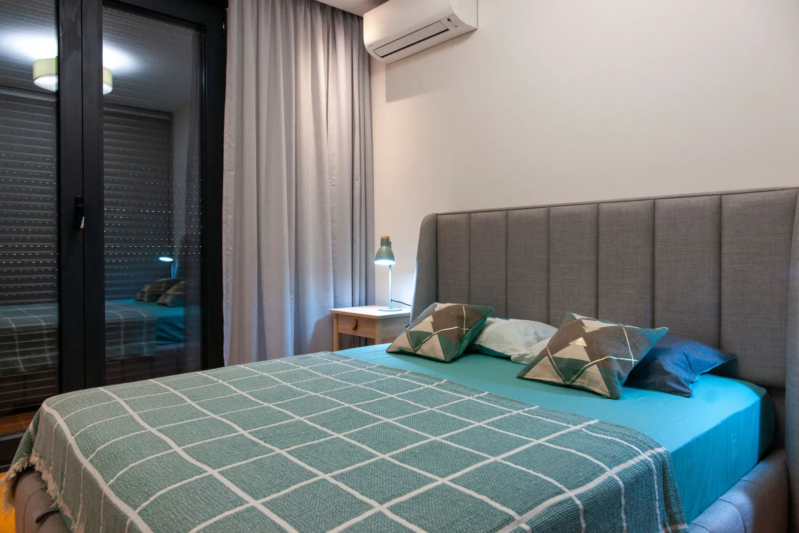 Modern bedroom featuring a double bed, bedside table, and air conditioning unit.