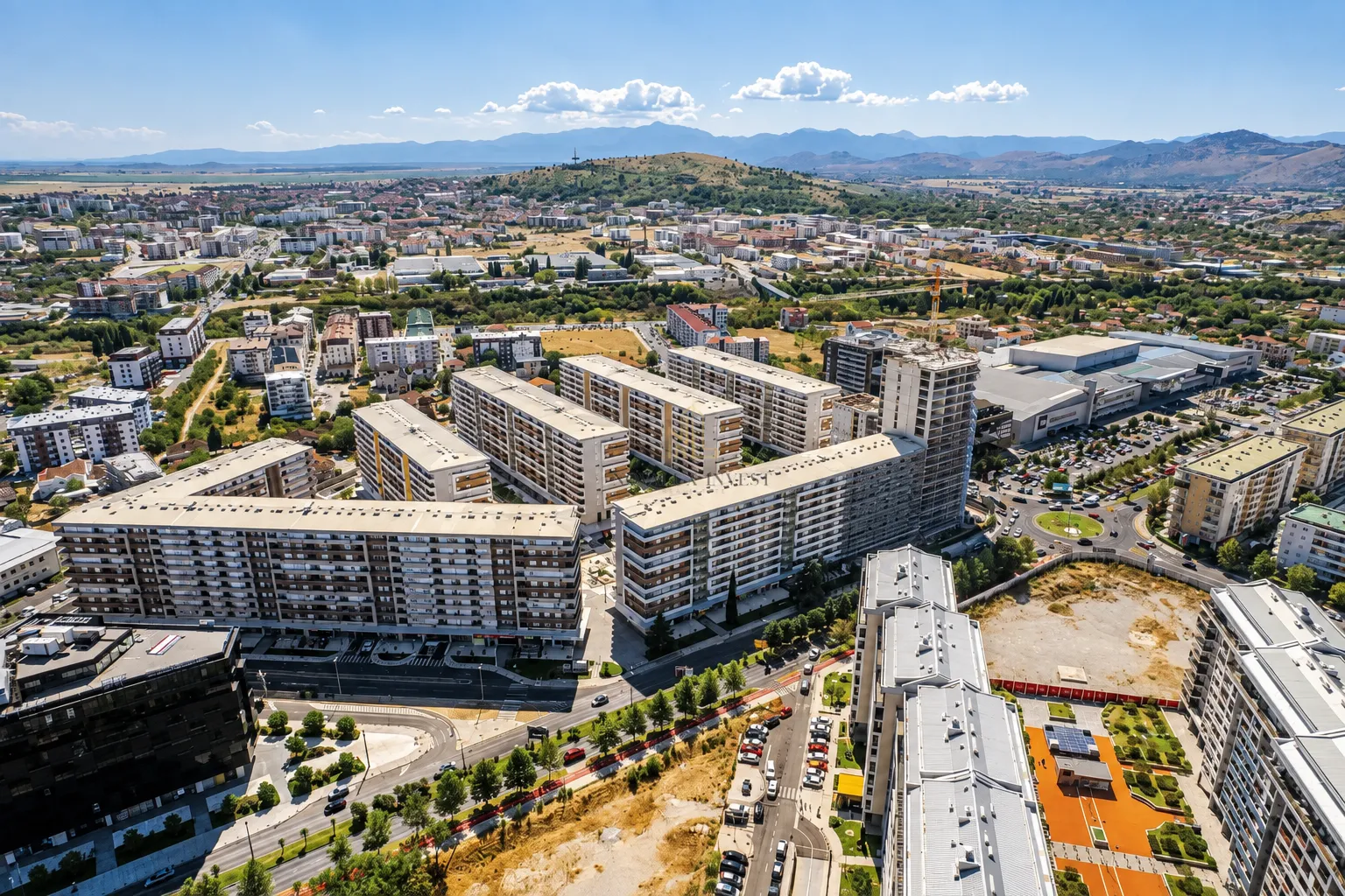 Pogled iz vazduha na gradsko naselje sa višespratnicama i okolinom.