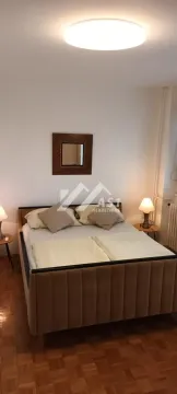 Spavaća soba sa bračnim krevetom, noćnim stočićima i ogledalom na zidu. - image 5