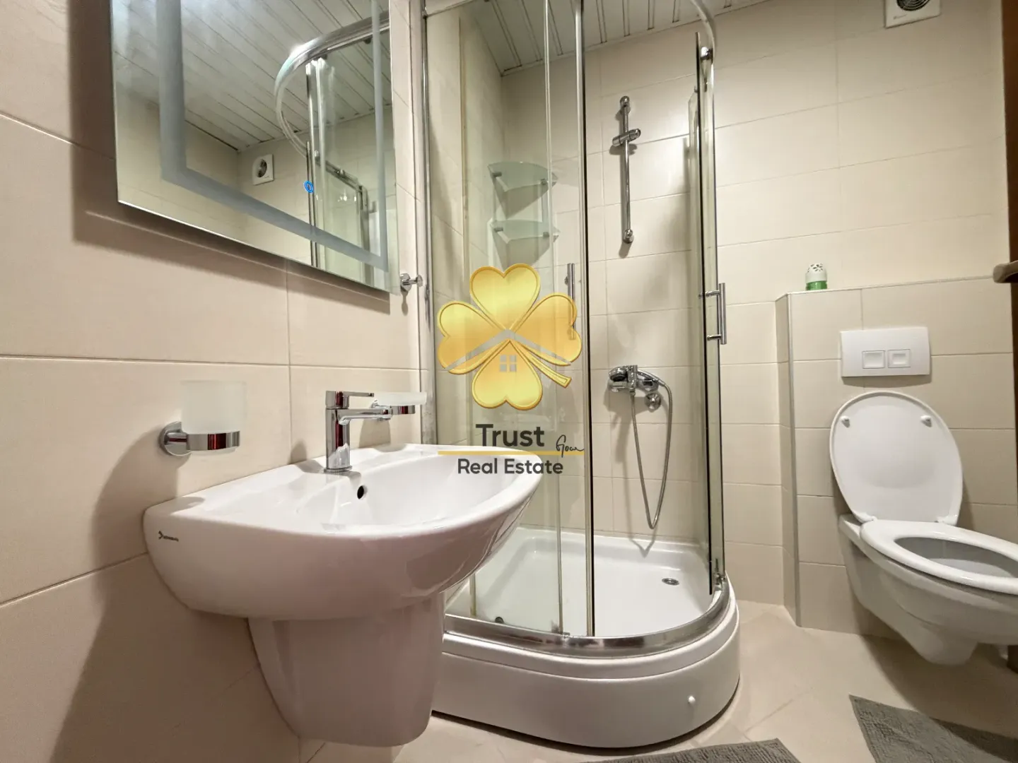 Modernly equipped bathroom with a shower cabin, washbasin, and toilet.