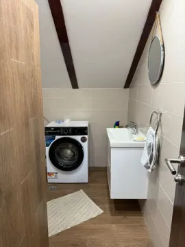 Compact bathroom with a sink and washing machine under a sloped ceiling. - image 5