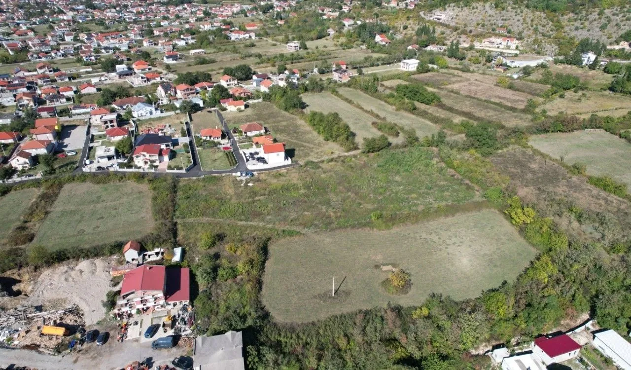 Pogled iz vazduha na zemljište i okolno naselje sa kućama.