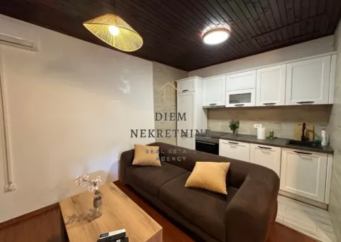 Living room with a sofa and a kitchen in the background. - image 3