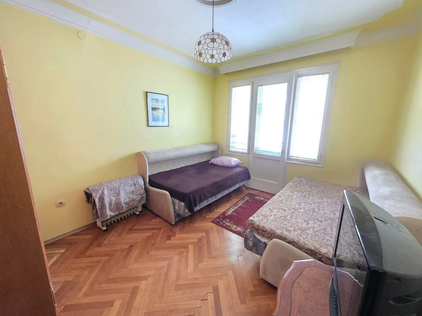 Furnished bedroom with beds and parquet flooring.
