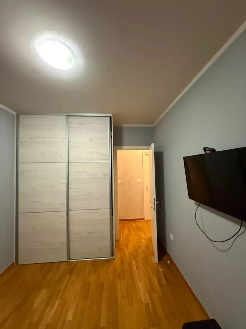 Spavaća soba sa ugradnim plakarom i televizorom na zidu.