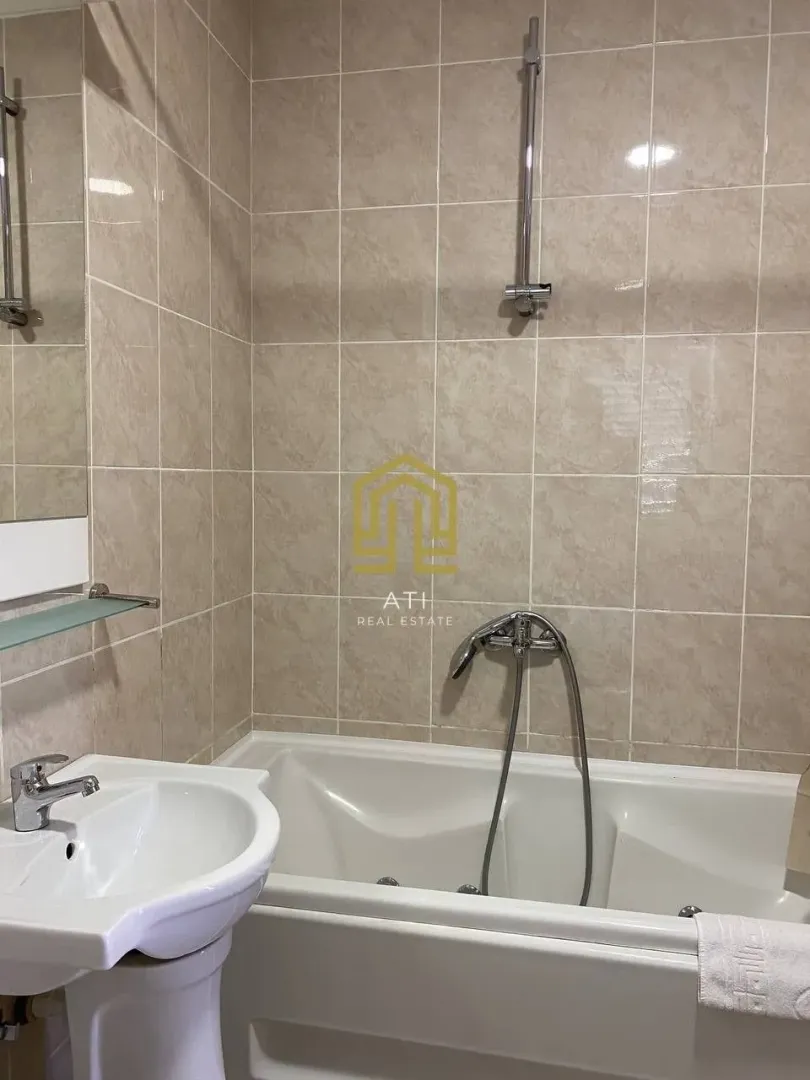 Bathroom with a bathtub and sink tiled with ceramic tiles.