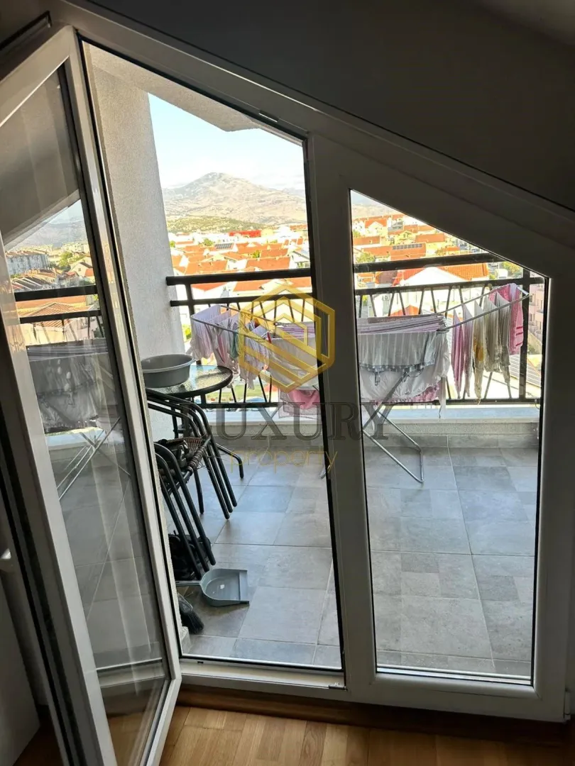 Manji popločani balkon sa sušilom za veš i pogledom na grad.