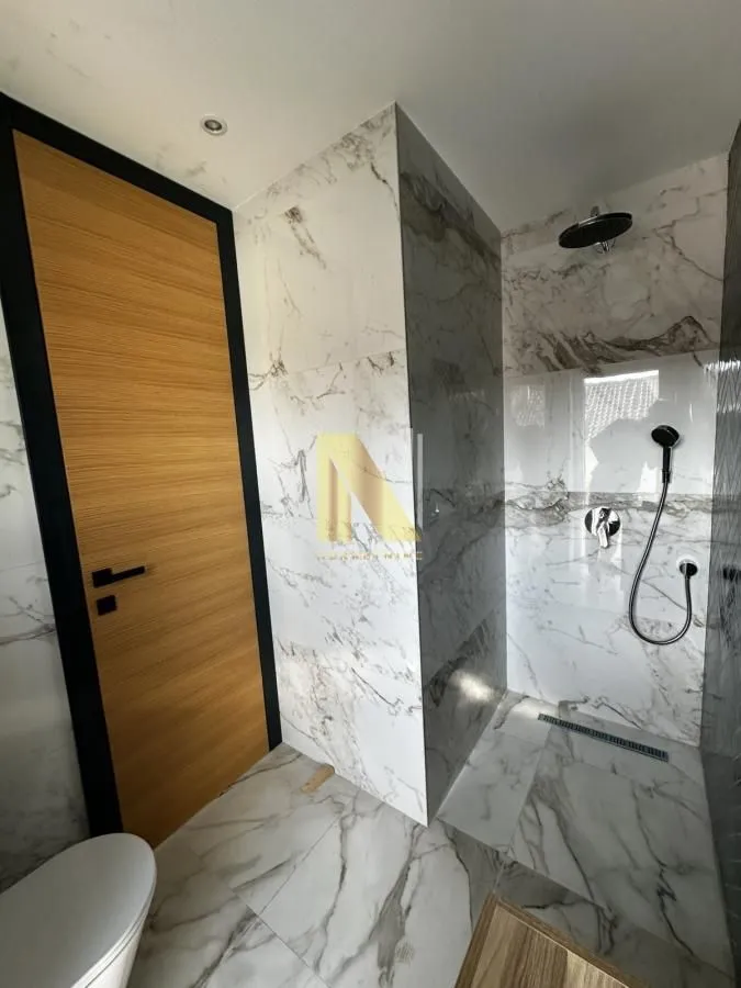 Modern bathroom with marble tiles and a walk-in shower.