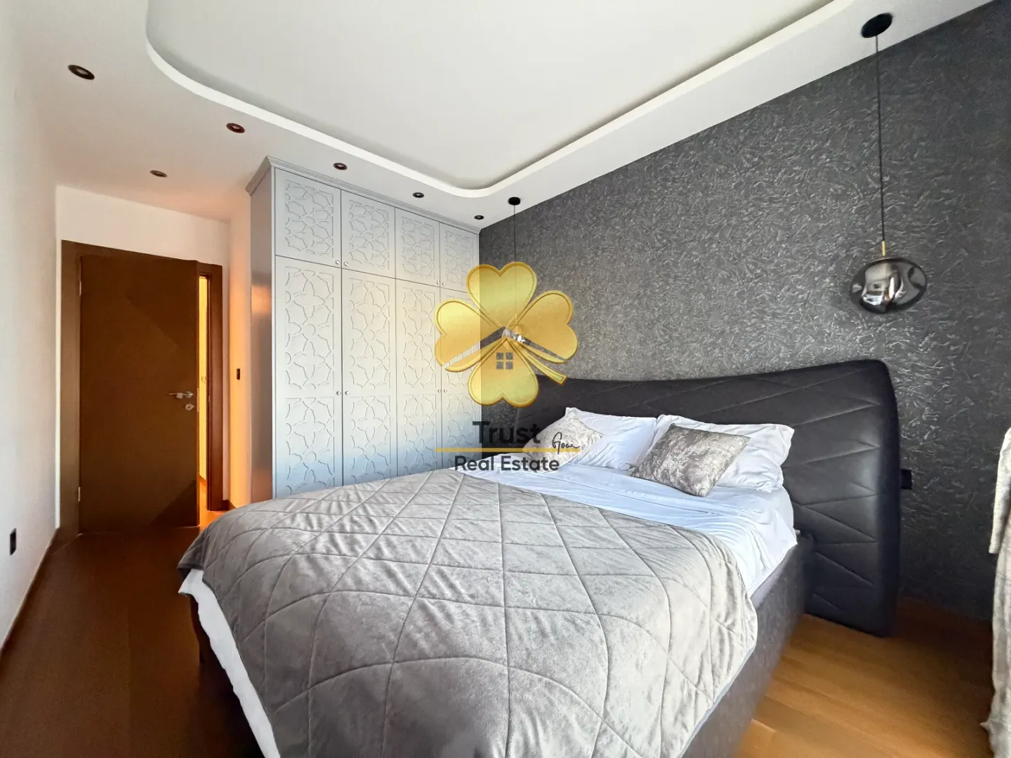 Modern bedroom with a double bed, wardrobe, and dark accent wall.