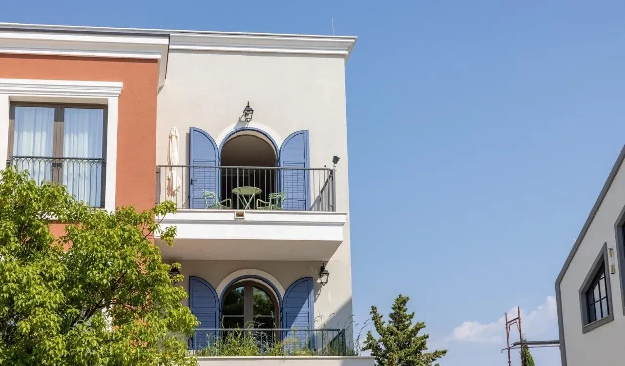 Eksterijer moderne višeporodične kuće sa plavim šalukatama i balkonima.