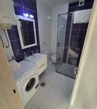 Modern bathroom with a walk-in shower, washbasin, and washing machine. - image 10