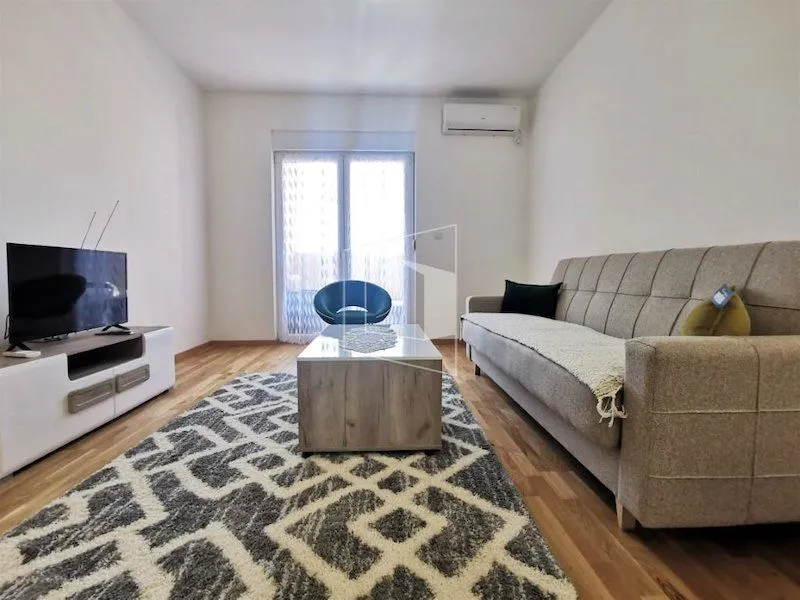 Living room with sofa, coffee table, TV, and air conditioning.