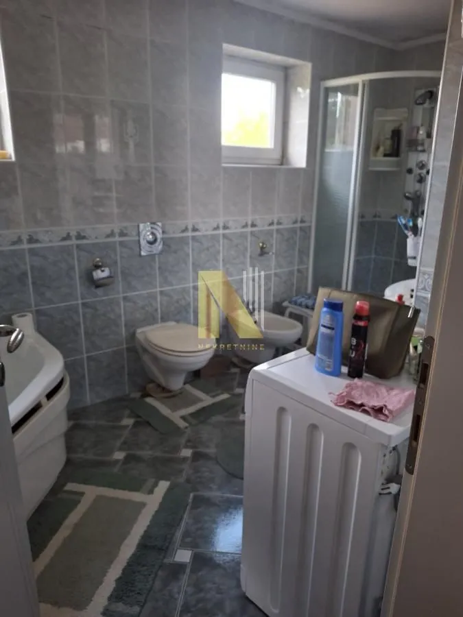 Kupatilo opremljeno sanitarijama, tuš kabinom i mašinom za veš.