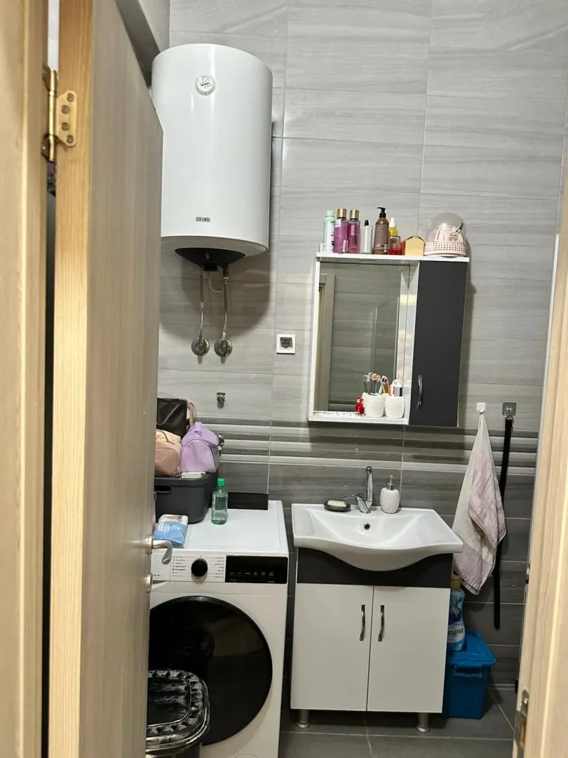 Pogled na kupatilo sa umivaonikom, mašinom za veš i bojlerom.