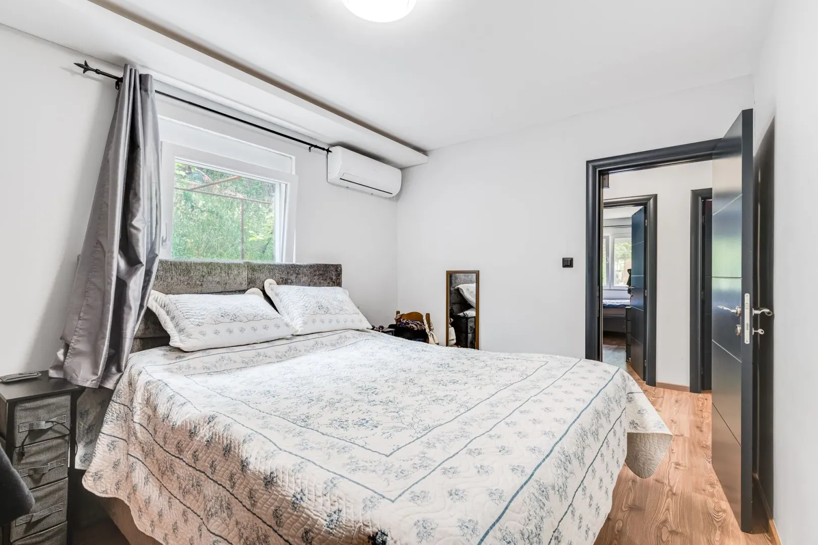 Bright bedroom with a double bed, window, and air conditioner.