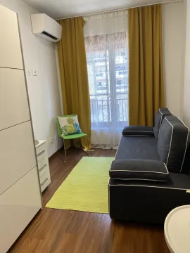 Mala dnevna soba sa tamnim kaučem, žutim zavjesama i zelenim tepihom. - image 7