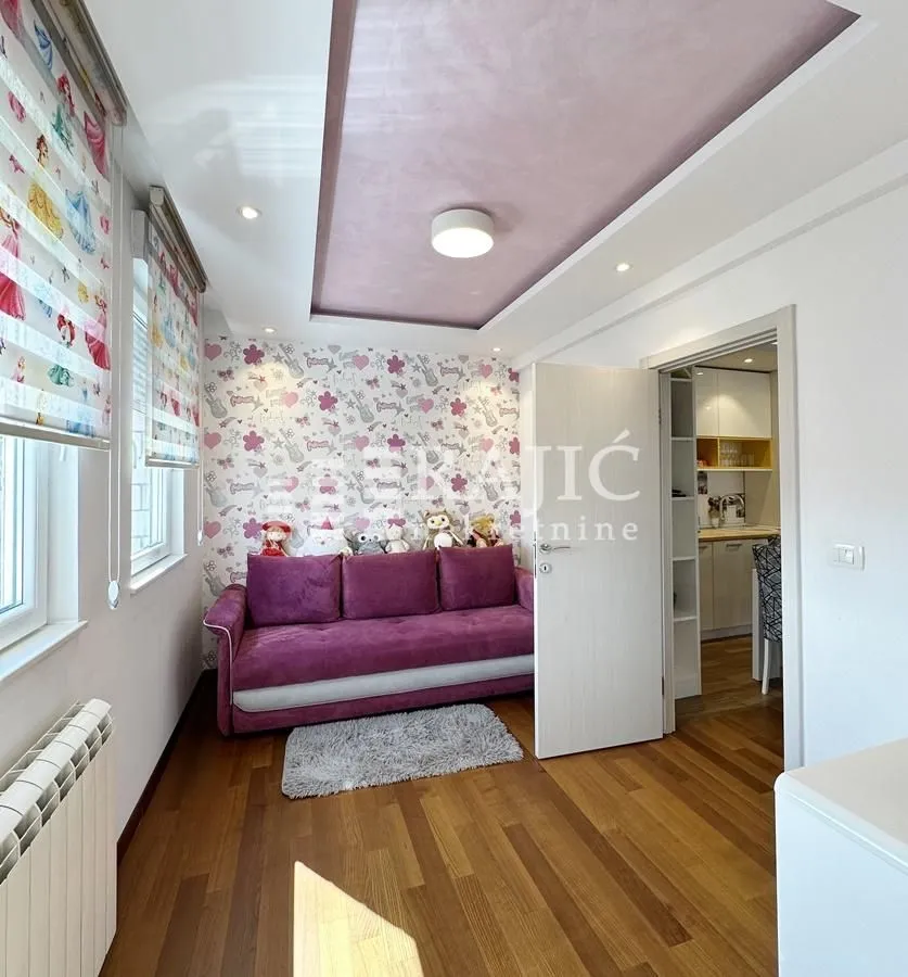 Children's bedroom with a purple couch and patterned wallpaper.