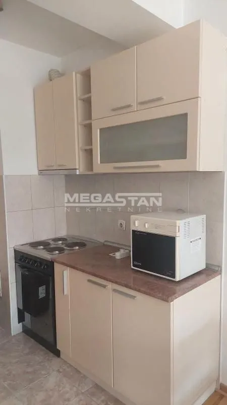 Small kitchen with beige cabinets and an electric stove.