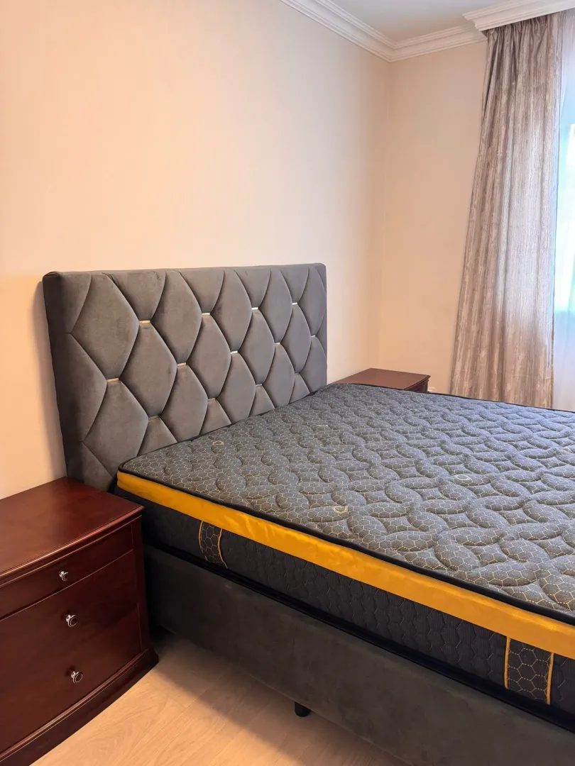A double bed with a tufted headboard and nightstands in the bedroom.