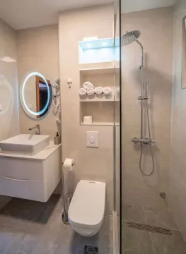 Modernly equipped bathroom with a shower cabin, sink, and toilet. - image 12