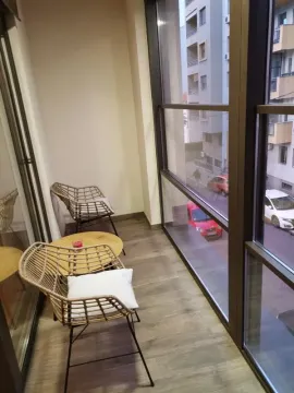 Small enclosed balcony with seating furniture and a street view. - image 4