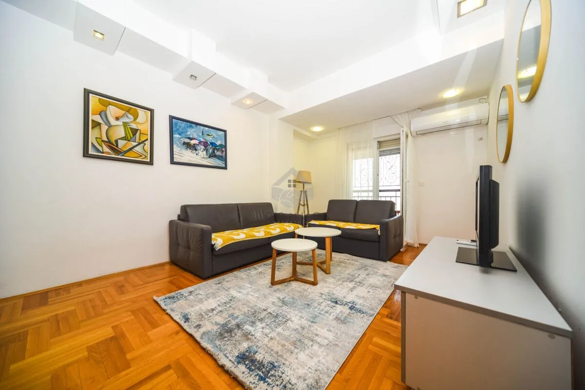 Living room with a sofa, coffee tables and a TV.