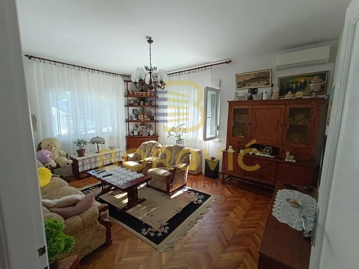 Dnevna soba sa garniturom za sedenje i drvenim nameštajem.