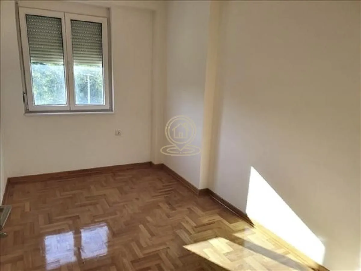 Prazna soba sa parketom i prozorom.