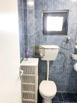 Manje kupatilo obloženo plavim pločicama sa toaletom i malim ormarićem. - image 8