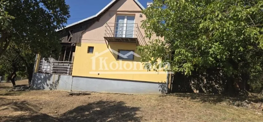 Pogled na spoljašnjost kuće sa dvorištem i zelenilom.