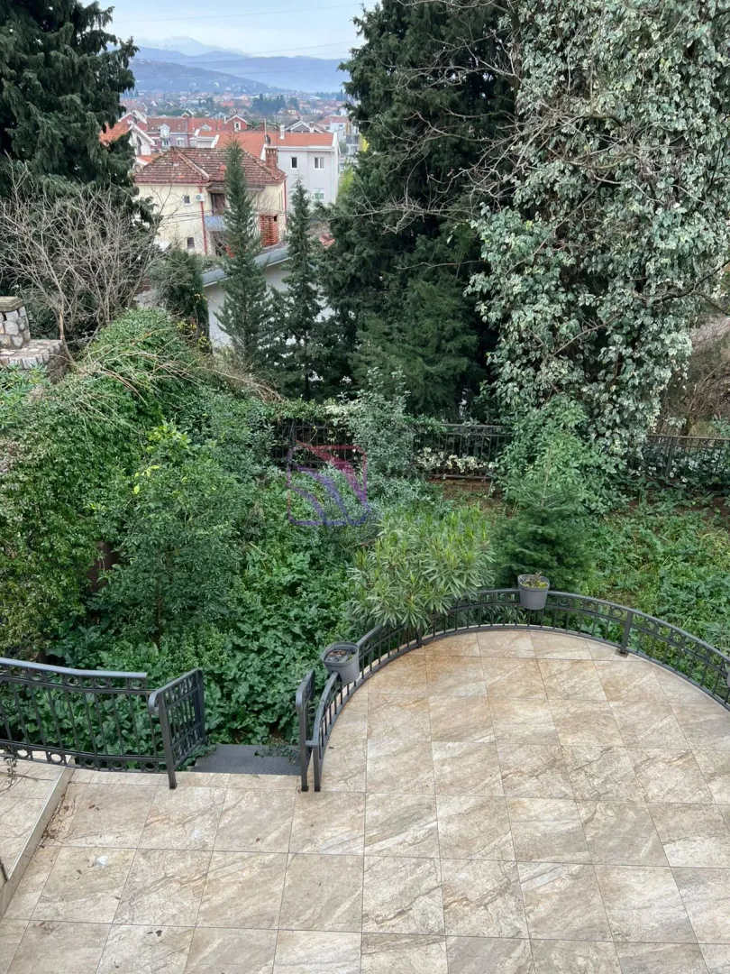 Popločana terasa sa ogradom i pogledom na dvorište i okolinu.